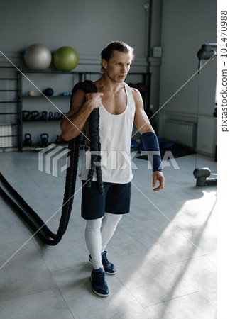 Young man with strong body shape carrying fitness ropes on shoulders 101470988