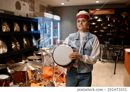 Young hipster woman choosing drum unit at musical shop feeling satisfaction 101471031