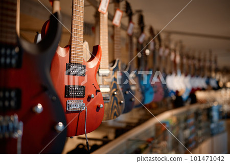 Electric guitars on the rack in a row at modern musical showroom Electric guitars on the rack in a row at modern musical showroom 101471042
