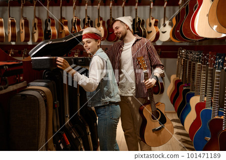Seller woman helping man buyer to choose guitar case at music store Seller woman helping man buyer to choose guitar case at music store 101471189