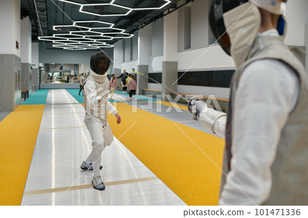Two swordsmen wearing uniform fighting duel during training in sport gym room 101471336