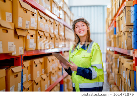 Portrait of young warehouse worker woman hold tablet and look to product boxes on her left side 101471879