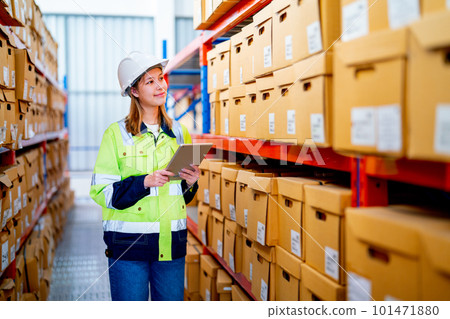 Pretty young warehouse worker woman hold tablet and look to product boxes on shelves of stock check Pretty young warehouse worker woman hold tablet and look to product boxes on shelves of stock check 101471880