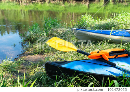 Tourist canoes with paddles stand on the river coast in summer on a water hike. Rafting on inflatable and frame double and triple kayak boats, family trip, extreme adventure in summer 101472053