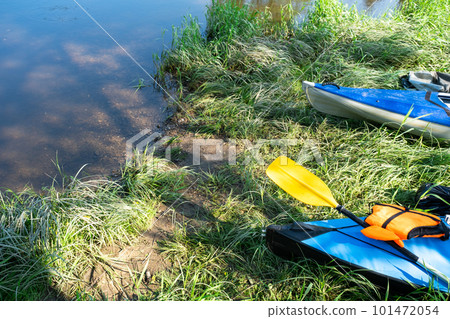 Tourist canoes with paddles stand on the river coast in summer on a water hike. Rafting on inflatable and frame double and triple kayak boats, family trip, extreme adventure in summer Tourist canoes with paddles stand on the river coast in summer on a water hike. Rafting on inflatable and frame double and triple kayak boats, family trip, extreme adventure in summer 101472054