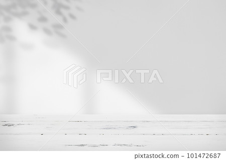 A room with a solid white table and sunlight streaming in through the window, casting shadows on the leaves. Simple background material. A room with a solid white table and sunlight streaming in through the window, casting shadows on the leaves. Simple background material. 101472687