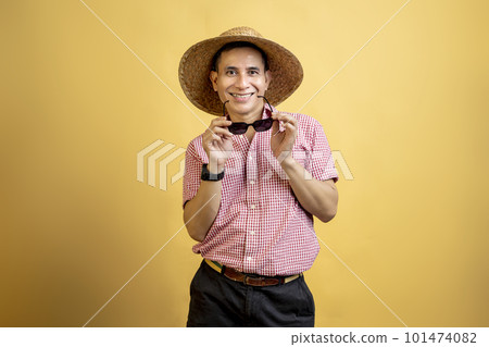 Man with a shirt and hat holding sunglasses standing Man with a shirt and hat holding sunglasses standing 101474082