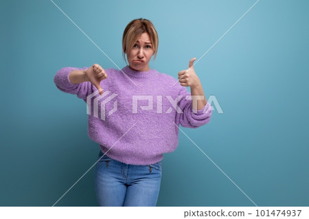 distressed upset blond young woman in purple hoodie showing like and dislike on blue background with distressed upset blond young woman in purple hoodie showing like and dislike on blue background with 101474937