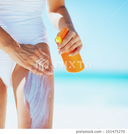 Closeup on young woman applying sun block creme on beach 101475270