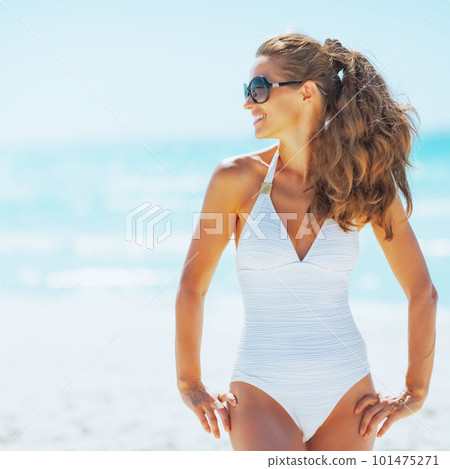 Young woman in sunglasses on beach looking on copy space 101475271