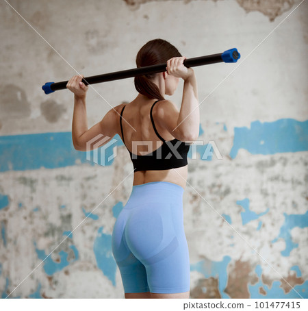 Sportive young girl with relief strong back, in sportswear training, doing hands exercises with fitness equipments indoors 101477415