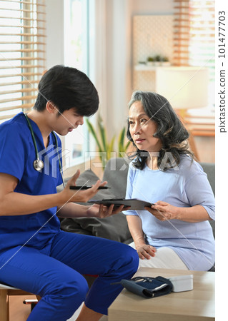 Medical worker giving a consultation, reporting medical results to middle age woman patient during home visit 101477703