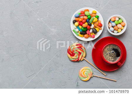 Coffee cup with chocolates and colored candy. Top view on table background with copy space Coffee cup with chocolates and colored candy. Top view on table background with copy space 101478970