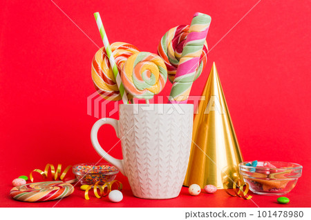 Colorful candies in cup on table on light background background. Large swirled lollipops. Creative concept of a jar full of delicious sweets from the candy store 101478980