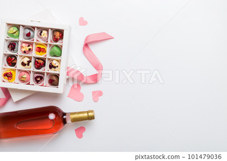 Bottle of red wine on colored background for Valentine Day with gift and chocolate. Heart shaped with gift box of chocolates top view with copy space Bottle of red wine on colored background for Valentine Day with gift and chocolate. Heart shaped with gift box of chocolates top view with copy space 101479036