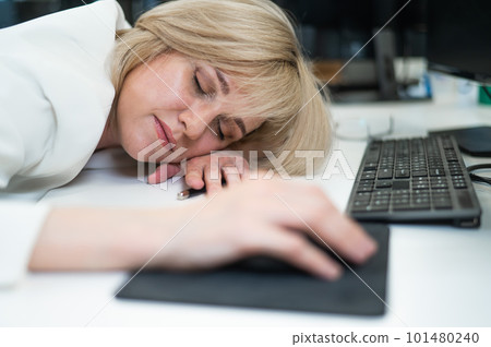 Caucasian blonde woman sleeping at her desk in the office.  101480240