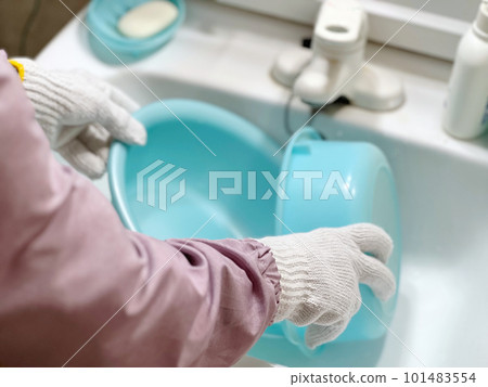 戴著手套的手在洗手間裡拿著一個盆 戴著手套的手在洗手間裡拿著一個盆 101483554