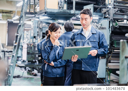 Staff discussing at the factory while looking at a tablet Staff discussing at the factory while looking at a tablet 101483678
