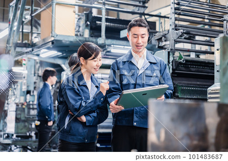 Staff discussing at the factory while looking at a tablet Staff discussing at the factory while looking at a tablet 101483687
