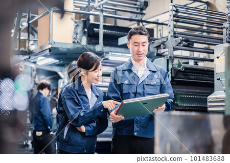 工廠員工一邊看著平板電腦一邊討論 工廠員工一邊看著平板電腦一邊討論 101483688