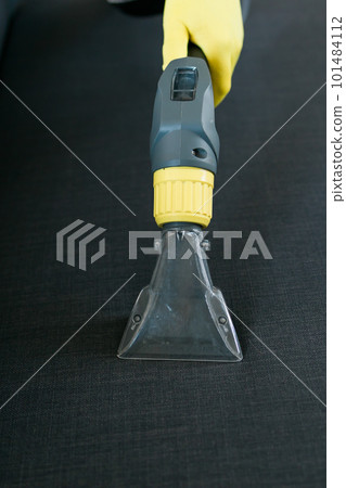 Cleaning service company employee removing dirt from furniture in flat with professional equipment. Man arm cleaning sofa with washing vacuum cleaner close up 101484112