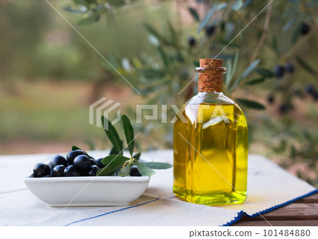 olive oil in a glass bottle and green olives on the background of olive branches in the garden 101484880