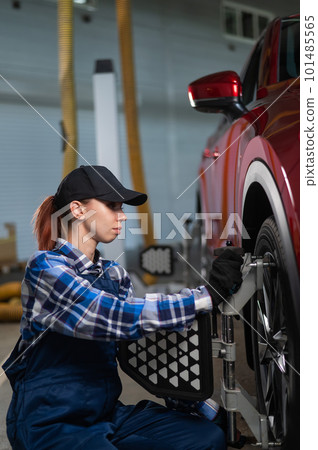A female auto mechanic makes a camber. Woman working in a car service. 101485565