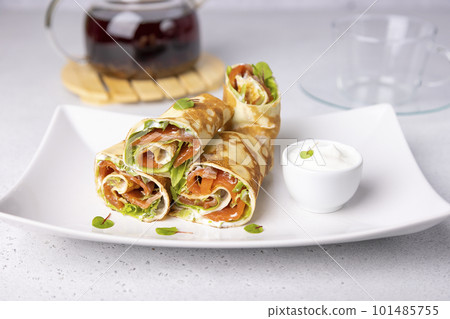 Pancakes with salmon (trout), sour cream, greenstuff and tea. Thin, not sweet blinchiki stuffed with red fish. Traditional Russian and Ukrainian dish. Feast of Maslenitsa. Selective focus, close-up. Pancakes with salmon (trout), sour cream, greenstuff and tea. Thin, not sweet blinchiki stuffed with red fish. Traditional Russian and Ukrainian dish. Feast of Maslenitsa. Selective focus, close-up. 101485755
