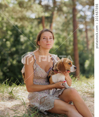 portrait of Caucasian woman and beagle dog in nature in park. cute pet having fun on vacation portrait of Caucasian woman and beagle dog in nature in park. cute pet having fun on vacation 101487898