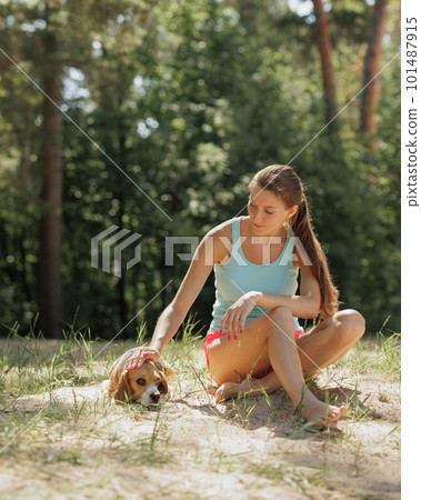 portrait of Caucasian woman and beagle dog in nature in park. cute pet having fun on vacation portrait of Caucasian woman and beagle dog in nature in park. cute pet having fun on vacation 101487915