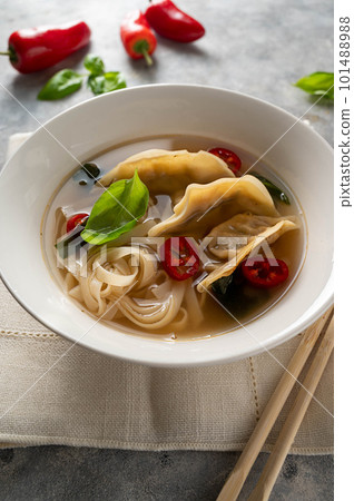 Spicy miso soup with dumplings and rice noodles in white bowl 101488988
