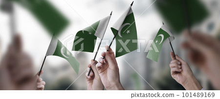 A group of people holding small flags of the Pakistan in their hands 101489169