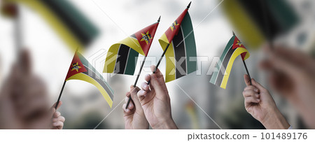 A group of people holding small flags of the Mozambique in their hands A group of people holding small flags of the Mozambique in their hands 101489176