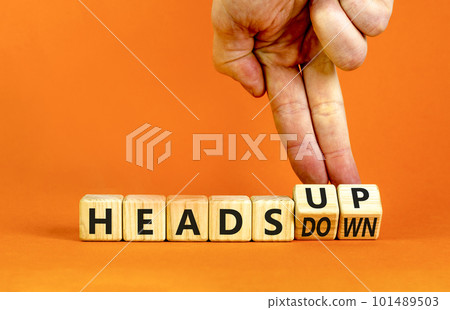 Heads up or down symbol. Concept words Heads up Heads down wooden cubes. Businessman hand. Beautiful orange table orange background. Business heads up or down concept. Copy space. Heads up or down symbol. Concept words Heads up Heads down wooden cubes. Businessman hand. Beautiful orange table orange background. Business heads up or down concept. Copy space. 101489503