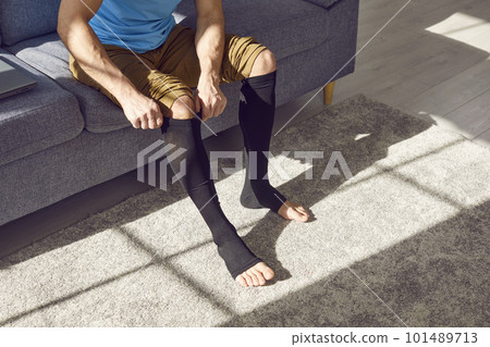 Young man with thrombosis or varicose puts on stretchable medical compression stockings Young man with thrombosis or varicose puts on stretchable medical compression stockings 101489713