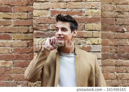 Young man wearing winter clothes in the street using a smartphone Young man wearing winter clothes in the street using a smartphone 101490165