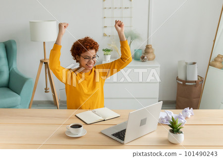 Excited happy african american woman euphoric winner. Girl student looking at laptop passed exam reading great news getting good result winning online bid feeling amazed at home. Winning gesture 101490243