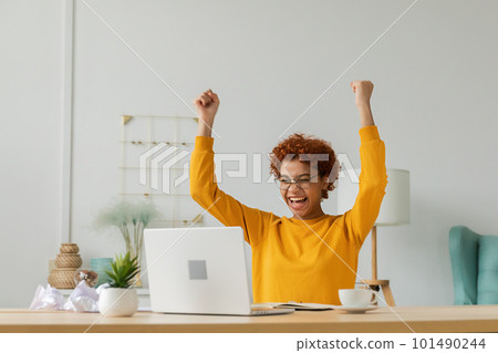 Excited happy african american woman euphoric winner. Girl student looking at laptop passed exam reading great news getting good result winning online bid feeling amazed at home. Winning gesture 101490244