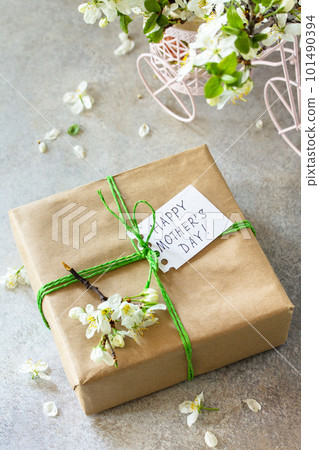 Mother's day or womens day background. Blooming cherry branch and a present with a congratulatory inscription that Happy Mother's Day on a gray stone table. 101490394