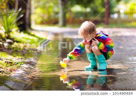 Kids in puddle in autumn rain. Waterproof wear Kids in puddle in autumn rain. Waterproof wear 101490484