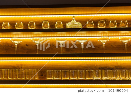 Glasses of wine. Glasses hanging above the bar in restaurant. Empty glasses for wine. Wine and martini glasses in shelf above bar rack in restaurant. night life Glasses of wine. Glasses hanging above the bar in restaurant. Empty glasses for wine. Wine and martini glasses in shelf above bar rack in restaurant. night life 101490994