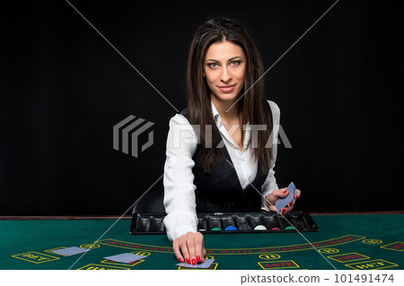 The beautiful girl, dealer, behind a table for poker The beautiful girl, dealer, behind a table for poker 101491474