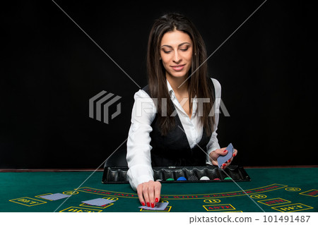 The beautiful girl, dealer, behind a table for poker The beautiful girl, dealer, behind a table for poker 101491487