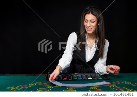 The beautiful girl, dealer, behind a table for poker The beautiful girl, dealer, behind a table for poker 101491491