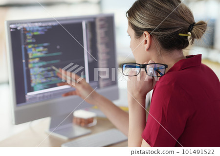 Female programmer checks code looking at screen of computer 101491522