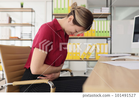 Woman feels acute stomach pain at workplace in office Woman feels acute stomach pain at workplace in office 101491527