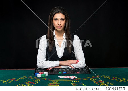 The beautiful girl, dealer, behind a table for poker The beautiful girl, dealer, behind a table for poker 101491715