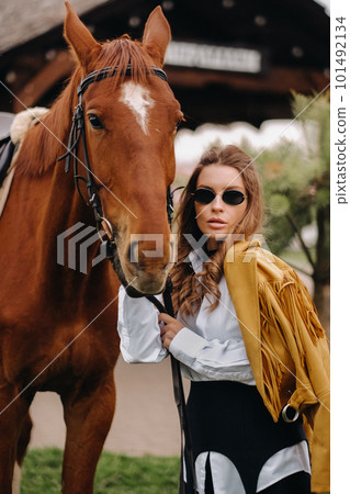 Stylish girl with glasses stands next to a horse on the street Stylish girl with glasses stands next to a horse on the street 101492134