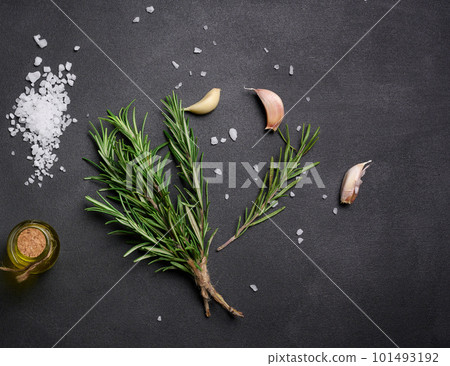 Scattered coarse white salt, peppercorns and rosemary sprigs on a black table, ingredients for cooking fish and meat Scattered coarse white salt, peppercorns and rosemary sprigs on a black table, ingredients for cooking fish and meat 101493192