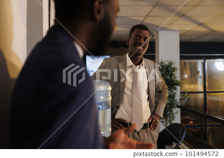 Businessman explaining marketing strategy to coworker during break time, team working overhours at company investment plan in startup office. Colleagues relaxing in modern workspace. Business concept 101494572